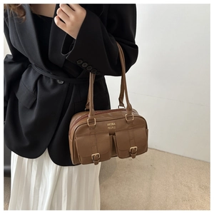 Detail of vintage brown shoulder bag featuring front pockets and golden buckles