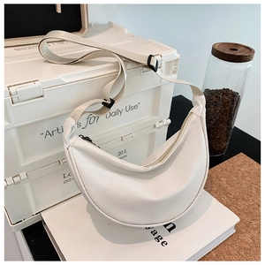 Detail view of a white nylon crescent crossbody bag with adjustable fabric shoulder strap