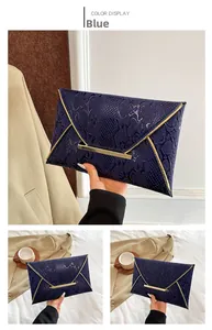 Macro detail of dark blue snake embossed envelope clutch bag with gold V-shaped metal trim