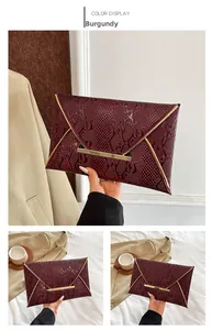Detail view of wine red envelope clutch with snakeskin texture and gold metallic trim