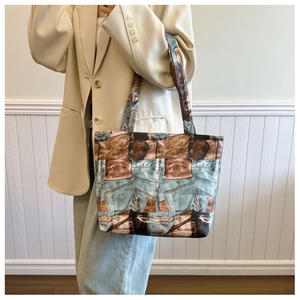 Close-up of printed denim tote bag styled with a cream blazer and blue jeans outfit