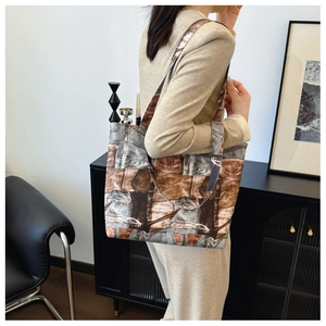 Detail of a large denim patchwork tote bag with vintage leather print on a female model