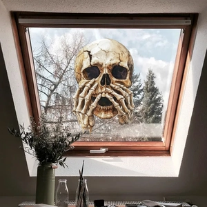 Realistic skull window sticker with boney hands on an attic glass pane for Halloween decoration