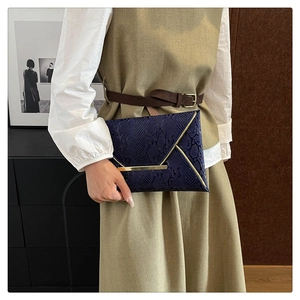 Detail of snake skin pattern handbag with elegant gold metal clasp and envelope design