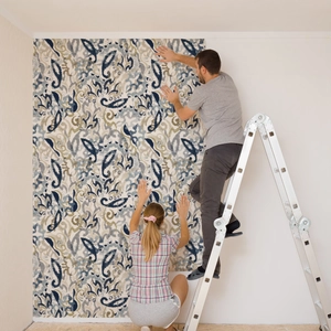 Close-up of vintage blue Paisley wallpaper being applied by hand on a white living room wall