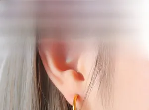 Close-up of 18K gold plated hoop earrings with zircon stones worn by a model
