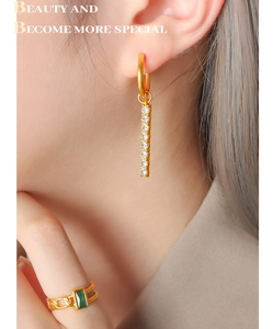 Detail of 18K gold earrings with vertical cubic zirconia stones worn by a model