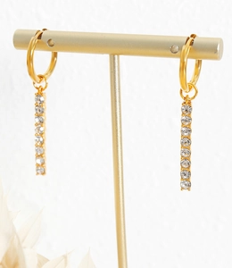 Close-up of gold geometric drop earrings with sparkling cubic zirconia on a jewelry stand