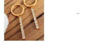 Close-up of 18K gold plated drop earrings with zircon crystals on dark wood background
