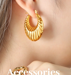 Détail de créoles dorées style croissant avec texture rainurée portées par un mannequin