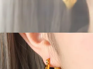 Gros plan d'un mannequin portant des boucles d'oreilles dorées en U à motif damier