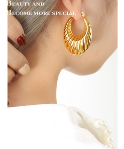 Détail rapproché des boucles d'oreilles dorées en forme de U avec motif torsadé chic