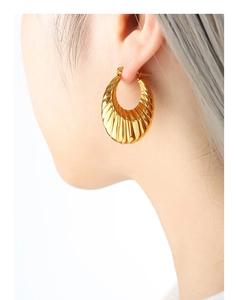 Détail d'une boucle d'oreille en U dorée avec des nervures verticales et fini brillant