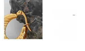 Gros plan de boucles d'oreilles dorées en U avec texture ondulée et fermoir sécurisé