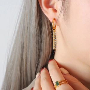 18K gold earrings with zircon pendants and ring with green gemstone on model
