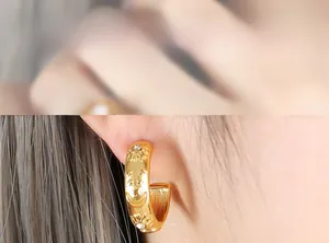 Detailed view of gold C-shaped earrings with sun and moon engravings and zircon stones