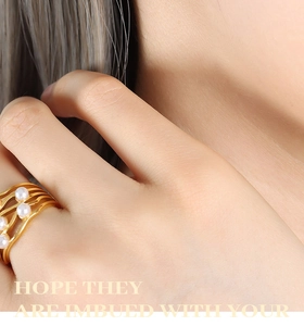 Detail of a vintage layered gold ring set with white pearls on a model's hand