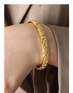 Close-up of gold bangle featuring embossed celestial motifs and sparkling zircon accents
