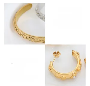 Detail of 18K gold plated titanium steel bangle and earrings with celestial relief
