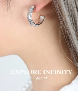 Detail of silver C-shaped earrings with sun moon and star relief on model ear