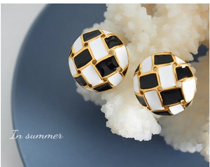 Close-up of retro black and white checkerboard round earrings with gold-plated edges