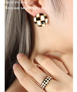 Detail of checkered heart earring and ring set in gold on a model for French vintage style