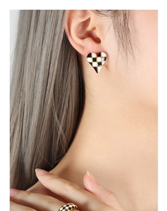 Detail of heart checkered earrings and ring with gold trim on model for a retro look