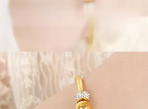 Detail of gold spiral open bangle with pavé crystals and polished bead on model