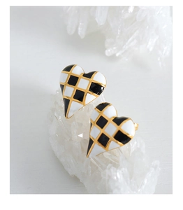 Detail of heart-shaped earrings featuring black and white checkerboard pattern with gold trim