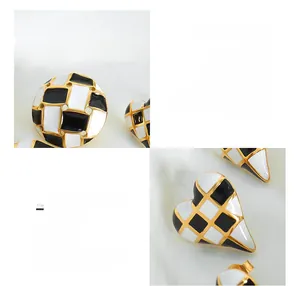 Macro shot of 18K gold plated heart and round checkered earrings in surgical titanium