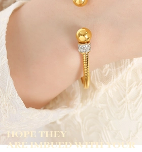 Macro shot of gold-plated spiral bangle with rhinestone-encrusted bead detail