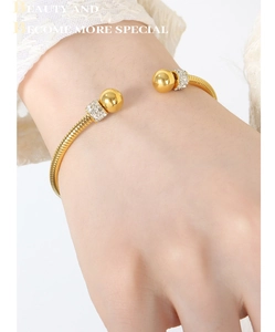 Detail of gold-plated snake-chain textured bangle with crystal-encrusted beads on wrist