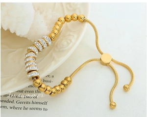 Bracelet ajustable en perles dorées avec strass brillants sur une assiette en céramique