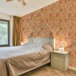 Detail der Vintage-Blumentapete mit rosa Rosen und grünen Blättern im Schlafzimmer-Ambiente