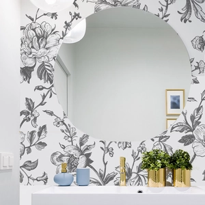 Detail of hand-drawn black floral wallpaper in a modern bathroom with a round mirror