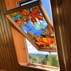 Macro detail of stained glass pumpkin and maple leaf window stickers on a bright skylight