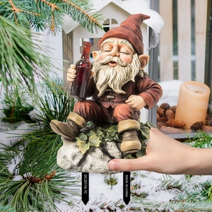Close-up of a Christmas gnome garden figurine with snowy pine and candle background