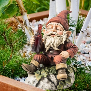 Detail of garden gnome statue with resin texture and red hat among outdoor greenery