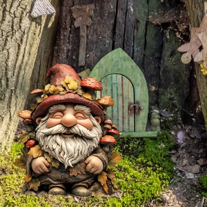 Macro shot of forest gnome stake with mushroom hat on mossy ground with miniature door