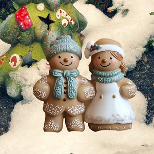 Gros plan de figurines de couple en pain d'épice dans la neige avec un sapin vert