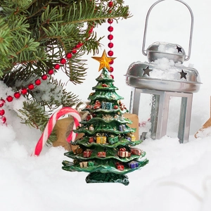 Macro view of a mini Christmas tree ornament with gift boxes on a snowy outdoor background