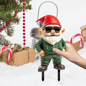 Christmas gnome garden stake with sunglasses and red hat placed in a snowy outdoor scene