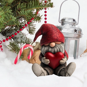 Close-up of a festive Christmas gnome sitting in a snowy setting with a red heart decoration