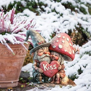 Garden gnome couple embracing a red heart with KISS carving in winter snow scenery