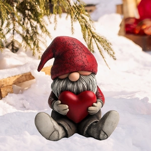 Close-up of a festive Christmas gnome garden stake with a red heart on snowy ground