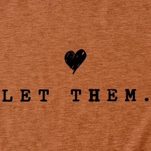 Detail of Let Them text and heart print on orange-brown knitted cotton t-shirt fabric