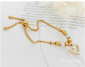 Detailed macro of gold-plated box chain bracelet with sparkling rhinestone heart charm