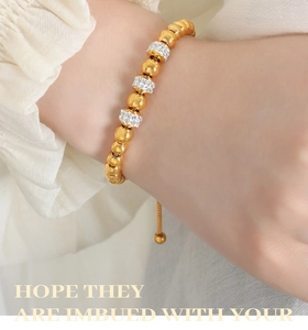 Détail d'un bracelet en perles d'or 18k réglable avec breloques scintillantes en zircon