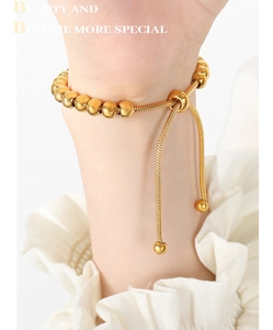 Détail d'un bracelet doré à billes réglable avec fermoir coulissant porté au poignet