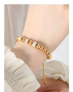Détail macro du bracelet à billes en or 18k avec breloques en strass et fermoir ajustable